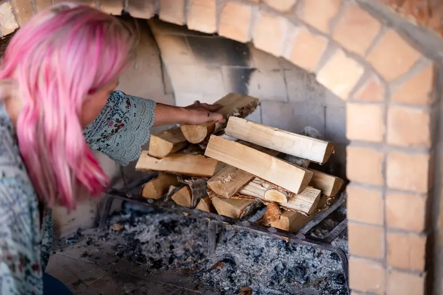 Erin placing wood into the stone hearth before the fire is lit — building the ritual fire