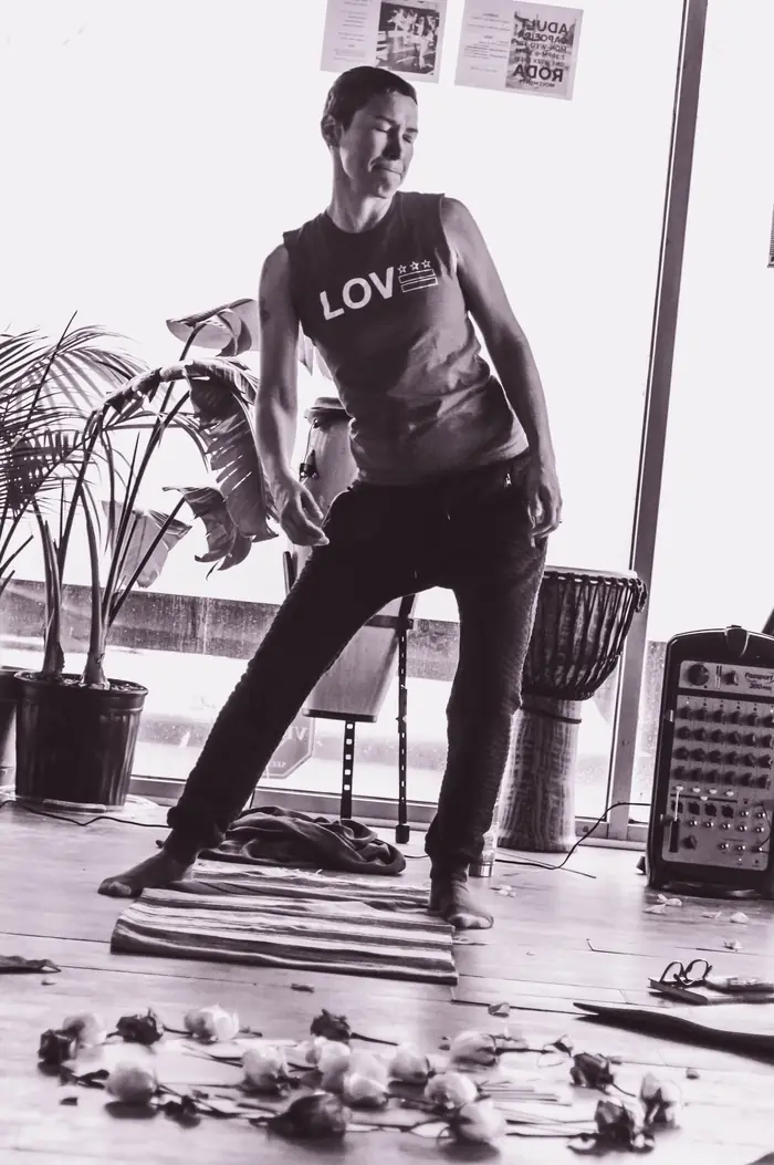 A woman dancing alone in a studio, rose petals at her feet